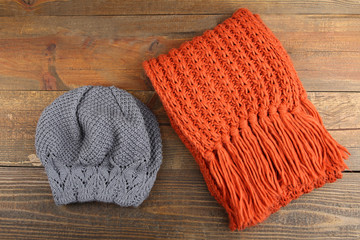 Knitted hat and scarf on wooden background