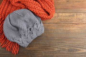 Knitted hat and scarf on wooden background