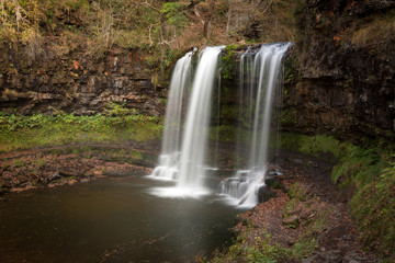 Obraz premium The Afon Hepste river plunges over a band of resistant gritstone to form the waterfall Sgwd yr Eira which translates into 'Fall of snow' and often refered to as the waterfall you can walk under. 