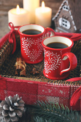 Cups of coffee and cinnamon sticks, burning candles and  pine co