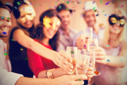 Composite image of cropped image of hands holding champagne flut