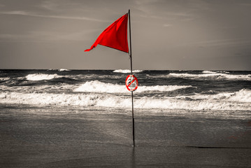 Red flag in ocean in selective color B&W, Lacanau, France