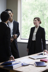 机を囲んで話すビジネスパーソン