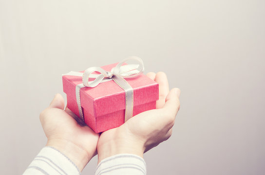 Closeup, Hand holding red gift box, female giving gift, New year holidays and greeting season concept, retro filter.
