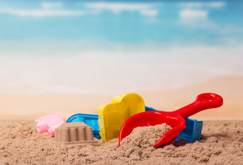 Fototapeta na wymiar Bright plastic toys and castle in sand against the sea.