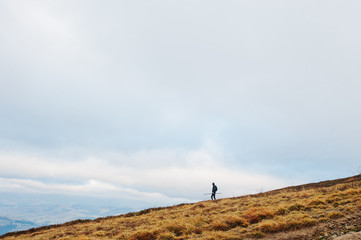 Obraz premium Man with a back pack walking down the mountain with stick at han