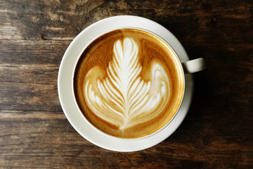 cup of latte art coffee on wooden background
