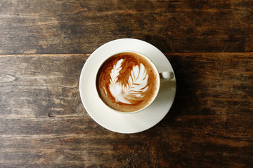 cup of latte art coffee on wooden background