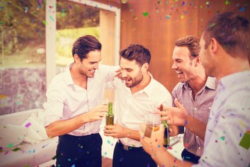 Composite image of men having drinks while standing together