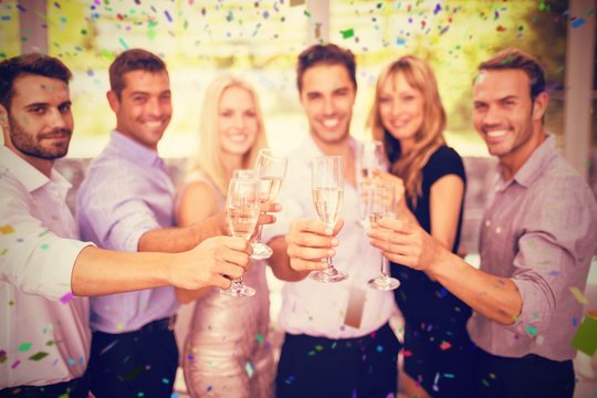 Composite image of group of friends holding glasses of champagne