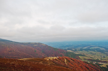 Scenic view of mountain autumn red and orange forests covering b