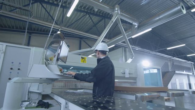 Engineer in Hard Hat Setting Up CNC Machine at the Factory. Shot on RED Cinema Camera in 4K (UHD)