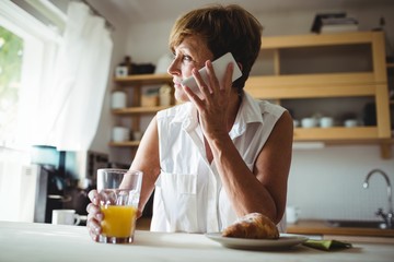 Fototapeta na wymiar Senior woman talking on phone while having breakfast