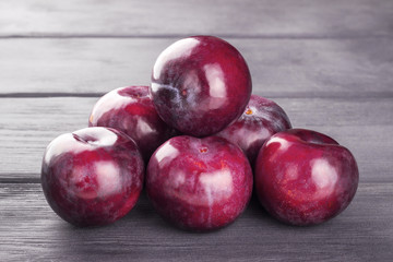 Ripe purple plums, on wooden background