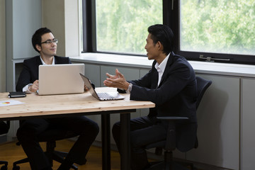 パソコンをしながら談笑するビジネスパーソン
