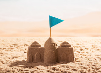 Fototapeta na wymiar Sand castle with flag on the sea shore.