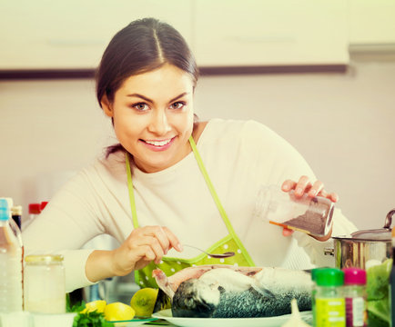 girl eviscerating salmon fish in domestic kitchen