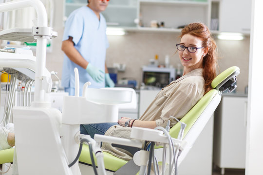 Young red hair  female patient sitting on dental chair and preparing for treatment.
