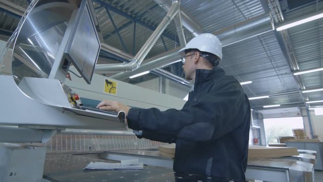 Engineer in Hard Hat Setting Up CNC Machine at the Factory