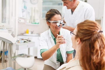 Female dentist in dental office talking with female patient and preparing for treatment.