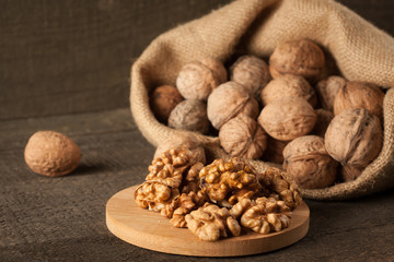 Walnut kernels in sack and whole walnuts on rustic old wood.