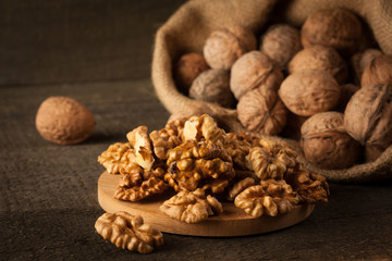 Walnut kernels in sack and whole walnuts on rustic old wood.