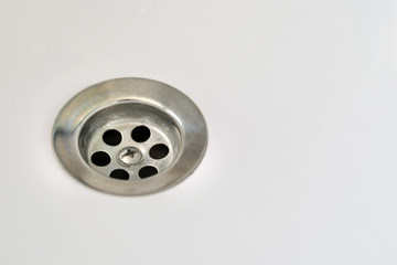 Drain in a white sink, background, close-up