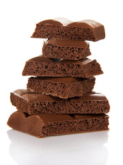 Stack of milk chocolate pieces isolated on white.