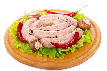 Wooden board with raw sausages, mushrooms, lettuce and pepper isolated.