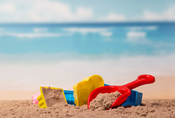 Bright children's toys in the sand against sea.