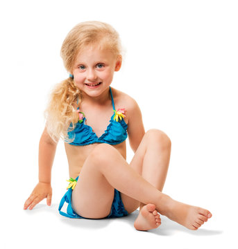 Seated little blond girl in swimsuit isolated on white background.