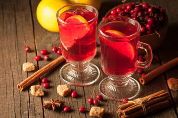 Two cups of red hot tea drink with fruits and spices on a wooden background. Mulled wine with cinnamon, anise and red berries. Winter hot drinks concept.