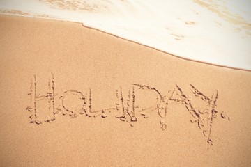 Holiday text on sand at beach