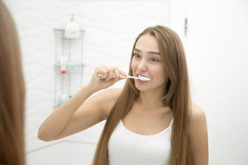 Portrait of a young girl cleaning her teeth, view over the shoulder, lifestyle. Beauty concept photo