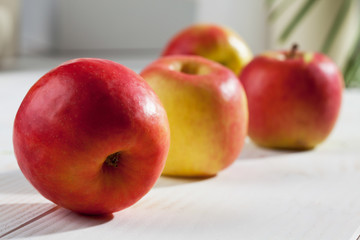 Rote Äpfel in einer Reihe auf weissem Holzuntergrund