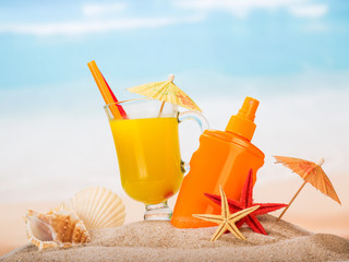 Glass juice, sunscreen, umbrellas, starfish, shells in sand against sea.