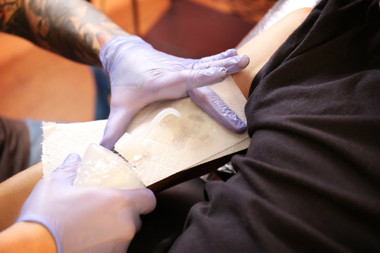 Hands of professional artist making tattoo in salon, close up view