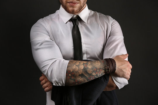 Naklejka Young tattooed man posing on dark background