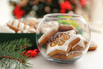 Glass vase with tasty gingerbread cookies on blurred background, close up view