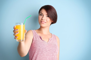 Young beautiful woman with glass of orange juice, on light background