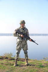 Naklejka premium Soldier with rifle standing at military firing range near river