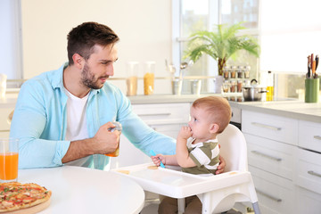 Father feeding small son on kitchen