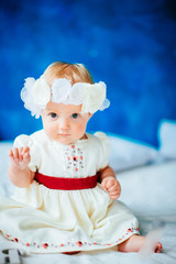 The baby sits on the bed in room