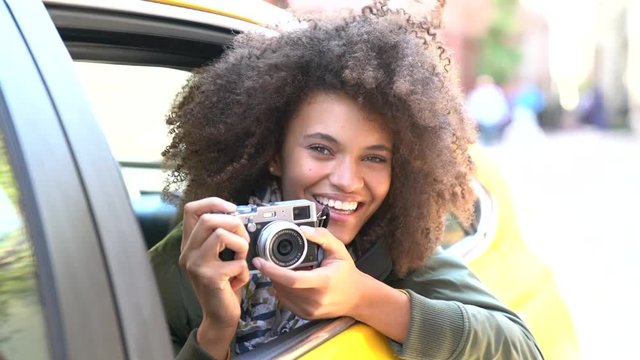 Cheerful girl taking pictures from a yellow cab, New York City