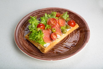 Plate of belgian waffles with salmon, tomatoes, herbs and balsamic vinegar