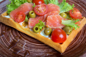 Plate of belgian waffles with salmon, tomatoes, herbs and balsamic vinegar