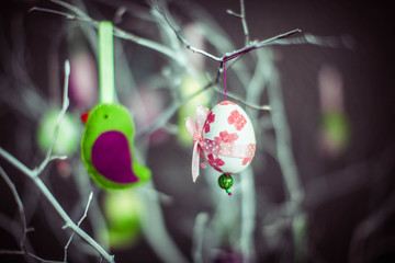 Easter egg and homemade soft bird hanging on white branches