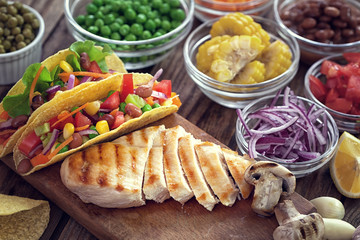 Mexican corn tortilla tacos with grilled chicken and vegetables on wooden background 
