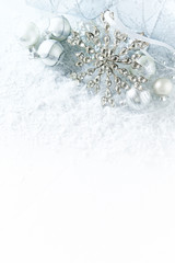 White and silver christmas decorations on a white surface with snow

