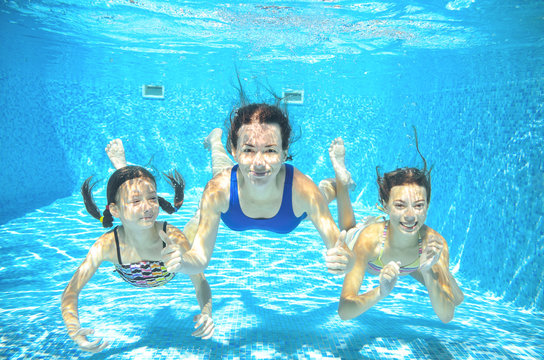 Family swims in pool under water, happy active mother and children have fun underwater, kids sport on family vacation
